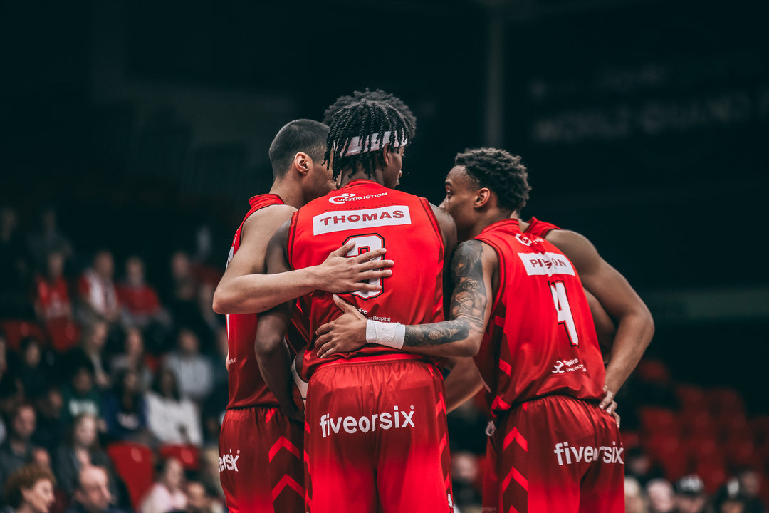 Basketball players huddled together in conversation wearing Kappa kit